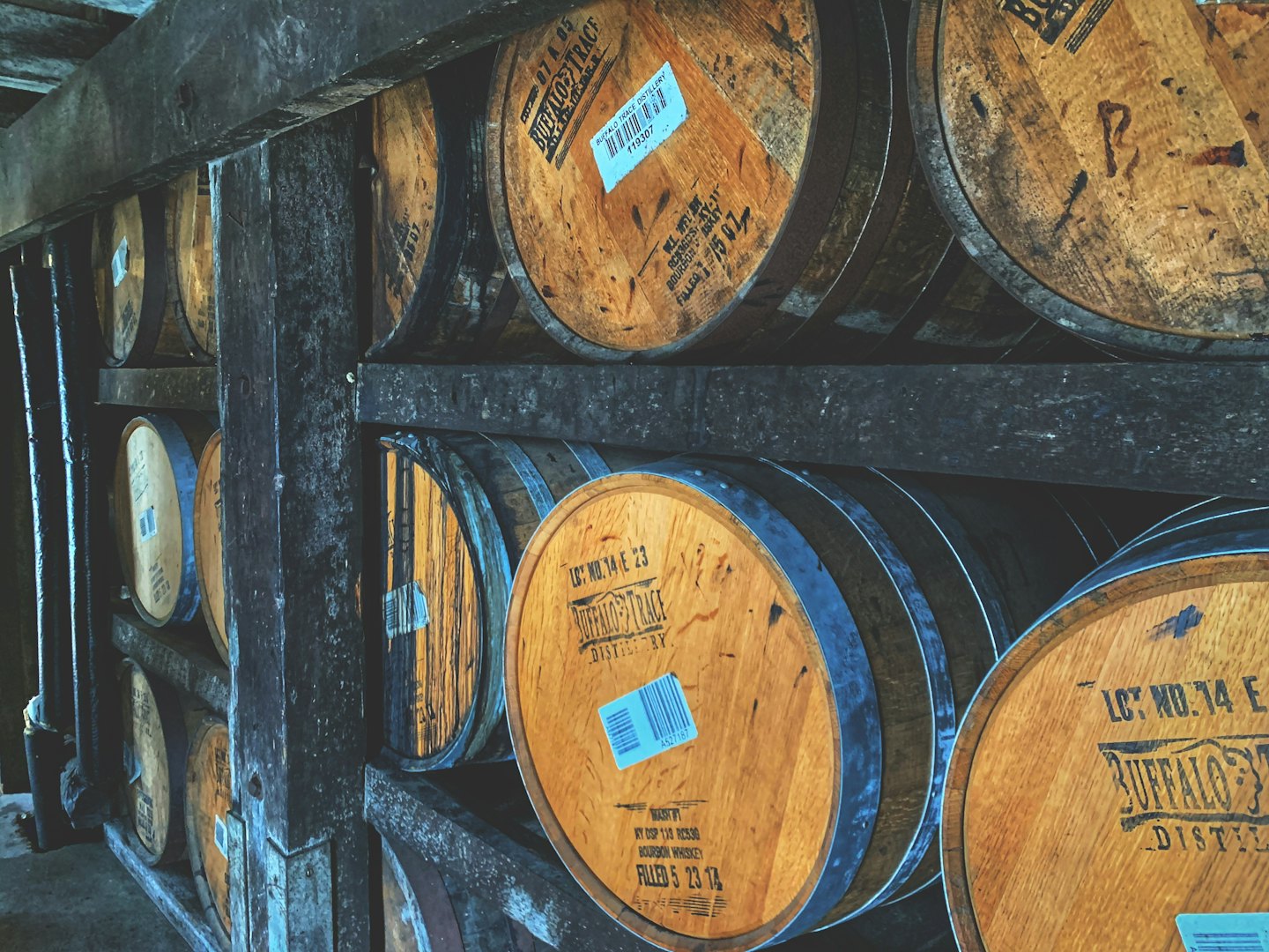 Barricas de whisky apiladas en estanterías de madera en un almacén.