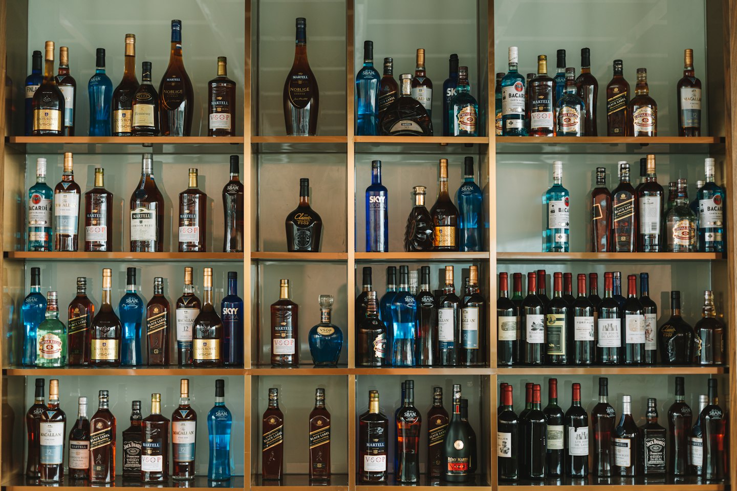 Botellas de licor variadas están ordenadas en estantes de madera.